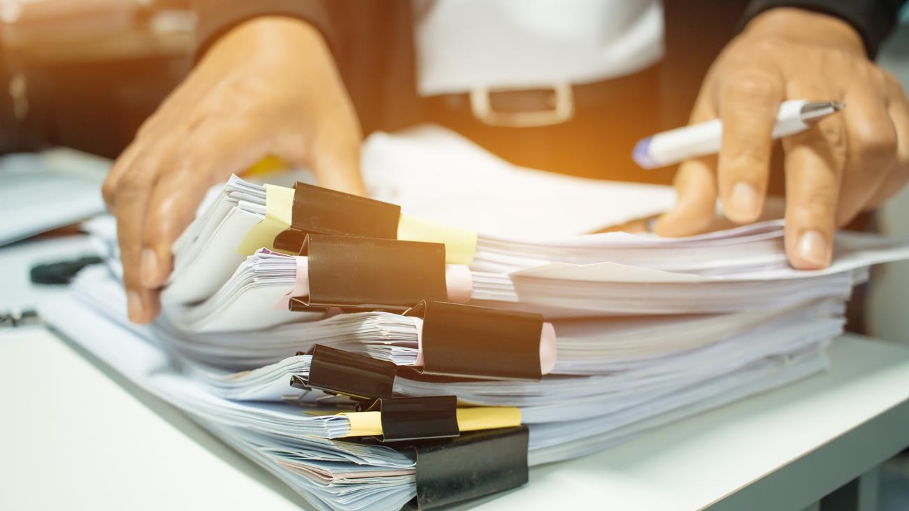 Businesswoman hands working on Stacks of documents files for finance in office. Business report papers or Piles of unfinished document achieves with black clip paper. Concept of Business Annual Report